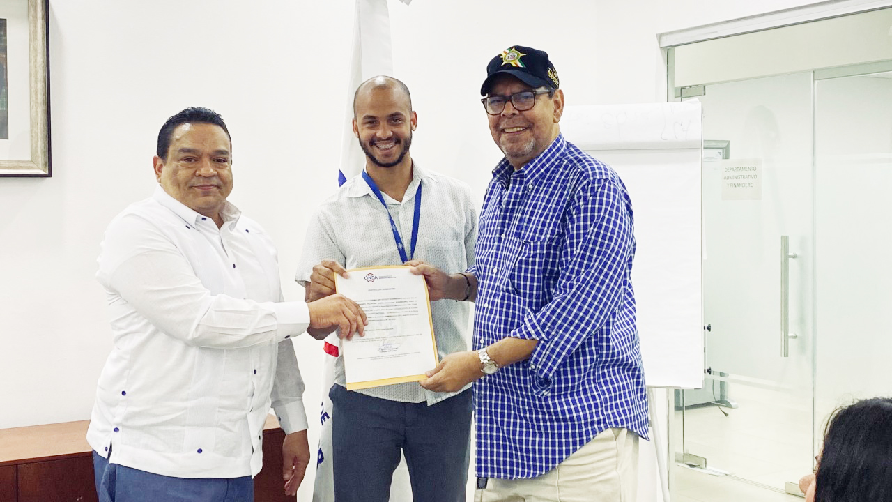 Gonell-Cosme-acompanado-de-Pablo-Portes-agente-de-atencion-al-usiario-entrega-el-certificado-a-Fernando-Villalona.
