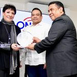 José Ruben Gonel Cosme y Armando Olivero entregan la placa de reconocimiento an Sophy.