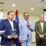 El licenciado José R. Gonell Cosme, entrega la placa al escritor doctor Antoliano Peralta, consultor Jurídico del Poder Ejecutivo.