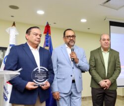 El licenciado José R. Gonell Cosme, entrega la placa al escritor doctor Antoliano Peralta, consultor Jurídico del Poder Ejecutivo.
