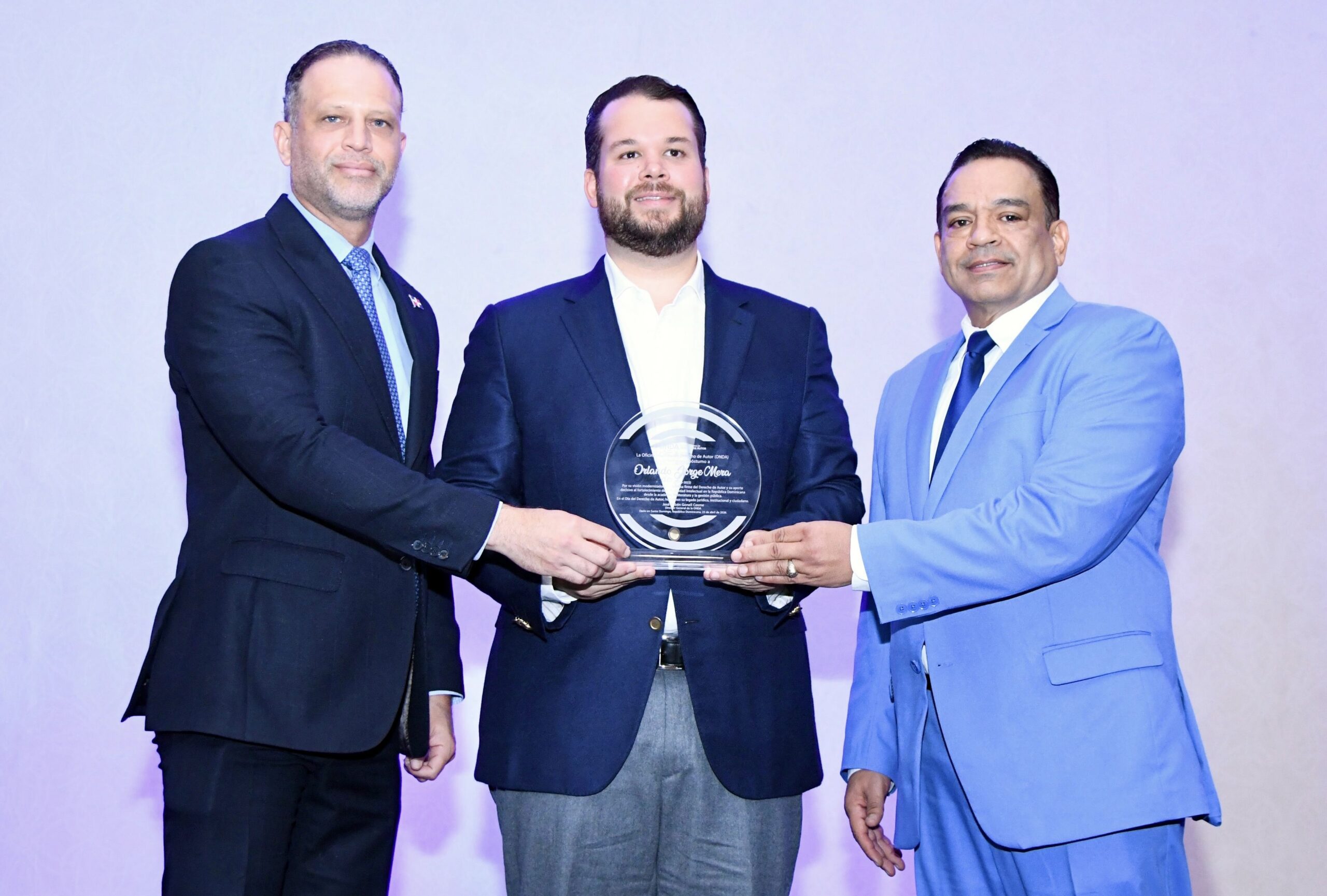 José Ruben Gonell Cosme, acompañado de Daniel Peña, viceministro de Industria Comercio y Mipymes (MICM), entrega una placa Orlando Jorge Villegas en hono0r a su padre Orlando Jorge Mera, en el homenaje póstumo que le fue rendido.